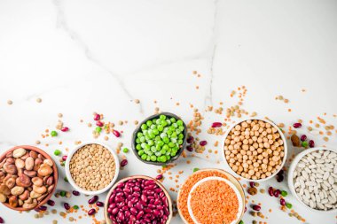 Baklagiller - fasulye, soya fasulyesi, nohut, mercimek, yeşil bezelye çeşitli ürün yelpazesine. Sağlıklı beslenme kavramı. Bitkisel proteinler. Beyaz mermer zemin kopya alanı üstten görünüm