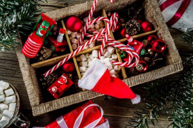 Klasik Noel arka plan, xmas ağacı süsler ve dalları, çocukların yılbaşı oyuncakları, şeker köpekler, çam kozalakları, eski ahşap masa üstten görünüm kopya alanı üzerinde santa şapka ve hediye kutuları