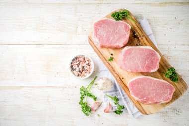 Pişirme et akşam yemeği arka plan. Çiğ taze et, domuz eti kemiksiz biftek, baharatlar, bitkiler, zeytinyağı, Beyaz ahşap zemin üzerinde görünümü top
