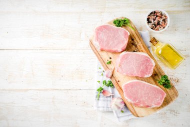 Pişirme et akşam yemeği arka plan. Çiğ taze et, domuz eti kemiksiz biftek, baharatlar, bitkiler, zeytinyağı, Beyaz ahşap zemin üzerinde görünümü top