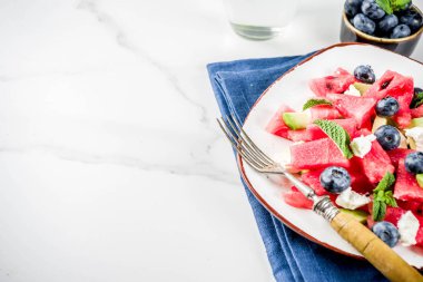 Yaz gıda kavramı, beyaz peynir, yaban mersini, avokado ve nane, beyaz mermer zemin kopya alanı ile taze soğuk karpuz salatası