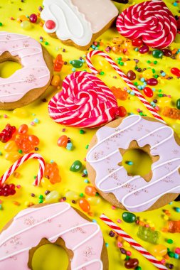 Tatlılar yaratıcı paralamak, lolipop, reçel, şeker, çerezleri çörek ve cupcakes, parlak sarı arka plana üstten görünüm kopya alanı ile tatlı kavramı