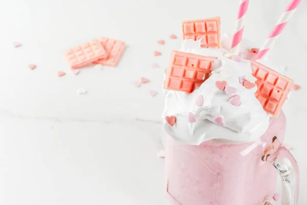 Crazy shake, romantic milkshake for Valentine\'s day with strawberry, white chocolate and sugar candy hearts, on white background, copy space