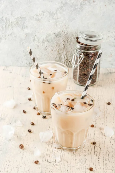 Summer cold Iced coffee frappe with milk and ice cubes, light concrete background copy space