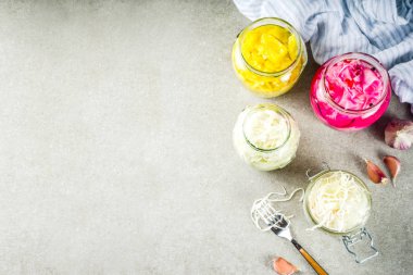 Fermente korunmuş Vejetaryen yiyecekler, çeşitli lahana turşusu koruyarak cam kavanozlar. Üç ev yapımı lahana turşusu gri taş masanın üzerine yazar. Kopya alanı.