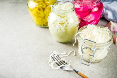 Fermente korunmuş Vejetaryen yiyecekler, çeşitli lahana turşusu koruyarak cam kavanozlar. Üç ev yapımı lahana turşusu gri taş masanın üzerine yazar. Kopya alanı.