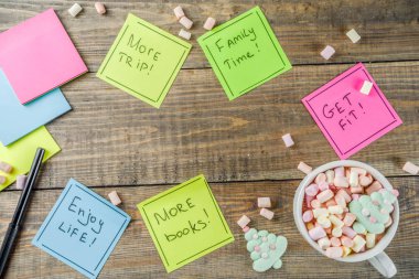 Yeni yıl kararları, renkli yapışkan notlar ile popüler yeni yıl kararlılık, ahşap arka plan ile komik sıcak çikolata Kupası, kopya alanı üstten görünüm flatlay