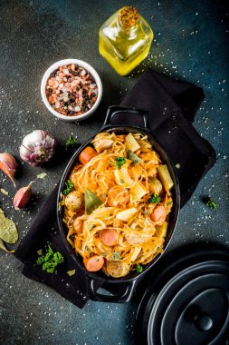 Almanca, Lehçe, Avusturya mutfağı yemek, Bigos - lahana lahana demlenmiş eti, mantar ve sosis, karanlık beton zemin üzerine küçük tavada. Kopya alanı ile üstten görünüm.