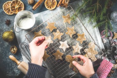 Kız yemek Noel ev yapımı kurabiye yıldız kurabiye, kurabiye adamlar, pişirme için aksesuarlar malzemelerle düz yatıyordu, en iyi görünüm. Koyu mavi beton arka plan kopya alanı, resimde eller