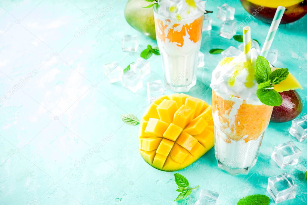 Tropical sweet dessert drink. mango milkshake or smoothie cocktail, with mango slices, mint and ice cubes, light blue background copy space