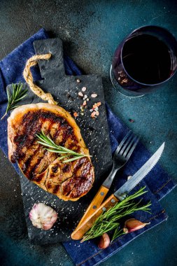 Et ve şarap ahşap kesme tahtası üzerinde çatal ile ızgara biftek dilimlenmiş. Koyu mavi arka plan. Üstten görünüm kopya alanı
