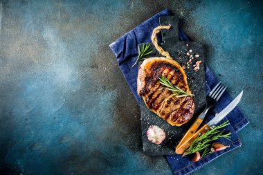 Et ve şarap ahşap kesme tahtası üzerinde çatal ile ızgara biftek dilimlenmiş. Koyu mavi arka plan. Üstten görünüm kopya alanı