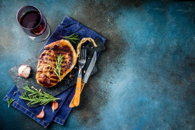 Et ve şarap ahşap kesme tahtası üzerinde çatal ile ızgara biftek dilimlenmiş. Koyu mavi arka plan. Üstten görünüm kopya alanı