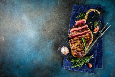 Et ve şarap ahşap kesme tahtası üzerinde çatal ile ızgara biftek dilimlenmiş. Koyu mavi arka plan. Üstten görünüm kopya alanı