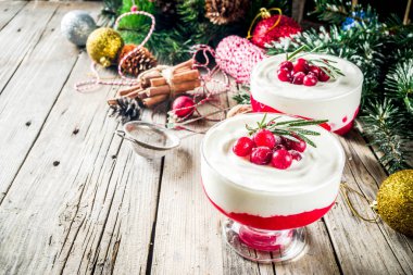 Noel yılbaşı arifesi kahvaltı tatlı, panna cotta veya bir bardak krem peynir, kızılcık reçeli, taze kızılcık cheesecake. Noel süslemeleri ile ahşap bir masa üzerinde alanı Kopyala