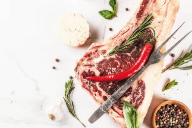 Ham sığır eti striplon kaburga eti baharat, otlar, beyaz mermer zemin üstten görünüm, kopya alanı ile mermer