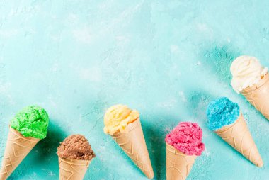 Çeşitli parlak renkli-dondurma dondurma koni - çikolatalı vanilyalı blueberry çilek fıstık turuncu ışık mavi güneşli arka planda, kopya alanı üstten görünüm seçimi