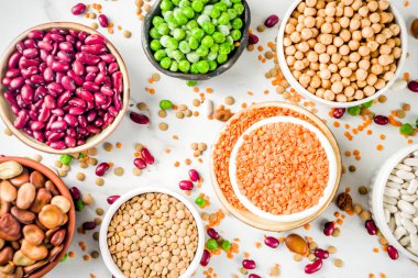 Baklagiller - fasulye, soya fasulyesi, nohut, mercimek, yeşil bezelye çeşitli ürün yelpazesine. Sağlıklı beslenme kavramı. Bitkisel proteinler. Beyaz mermer zemin kopya alanı üstten görünüm
