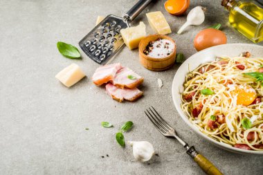 Geleneksel İtalyan Makarna, spagetti carbonara pastırma, krem sos, parmesan peyniri, yumurta sarısı ve taze fesleğen yaprakları gri taş arka plan kopya alanı
