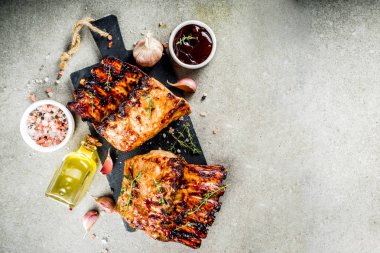 Izgara et kavramı. Barbekü domuz kaburga Barbekü sosu, zeytin yağı ile. gri taş zemin üzerine taze otlar alanı Kopyala