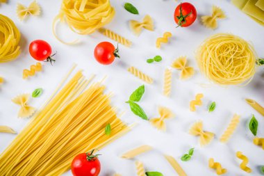 İtalyan gıda kavramı, çeşitli ham makarna çeşitler - spagetti, lazanya, düdük, tagliatelle, penne, tortellini, ravioli, domates ve fesleğen ile beyaz arka plan kopya alanı üstten görünüm bırakır