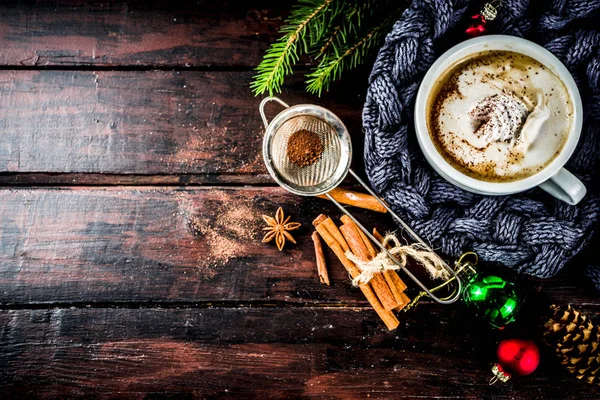 Spicy cappuccino coffee with for cold winter and autumn day. Xmas morning concept. Classic wooden background with christmas tree and decorations, copy space top view