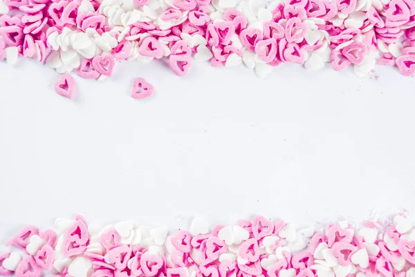 Valentine\'s sweets background, white background with sugar hearts sweet sprinkles, copy space top view, layout on white