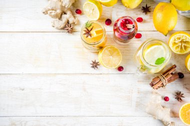 Çeşitli sonbahar ve kış serinletici su, tatlı ekşi sağlıklı içecekler portakal, bal, kızılcık, nane, biberiye, tarçın ve baharatlar, Beyaz ahşap arka plan kopya alanı ile infüzyon