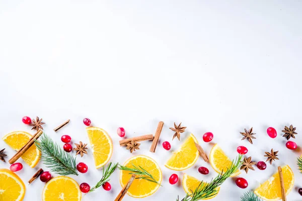 Winter autumn drink and food ingredients. Cranberries, sliced oranges, cinnamon, rosemary, anise for cooking cocktails, with christmas tree branches. Flatlay on white background. Top view copy space