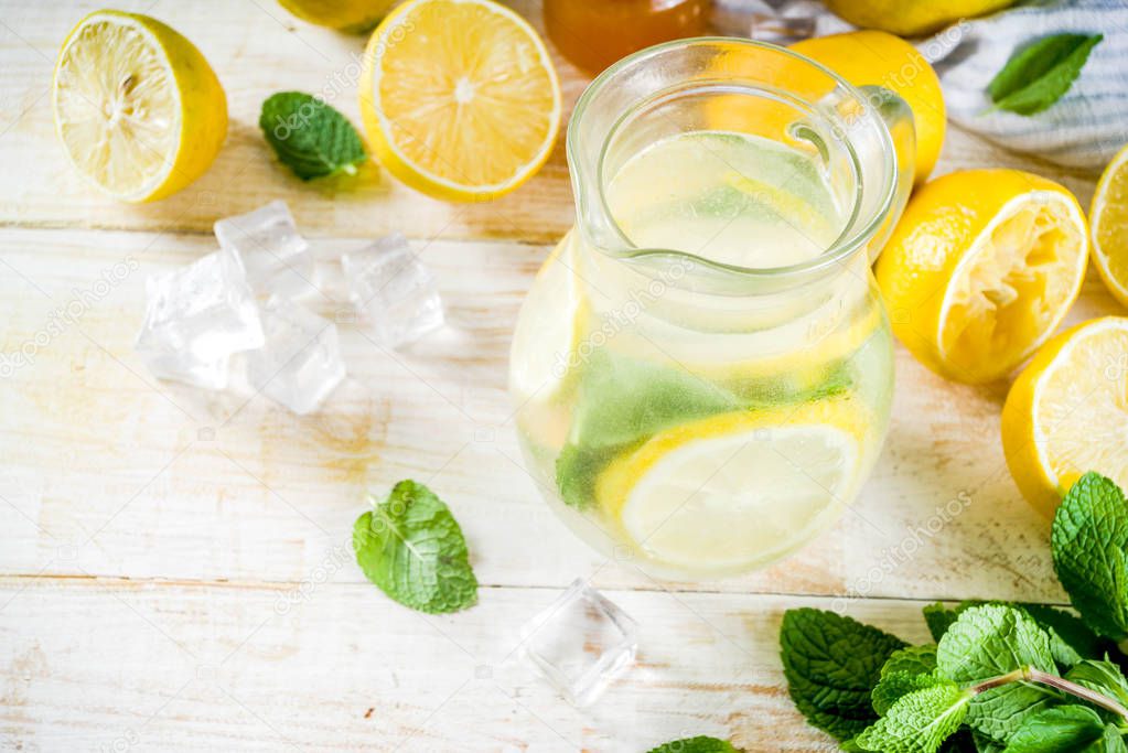 Homemade sour cocktail lemonade, with fresh lemons, mint and honey, white wooden background copy space
