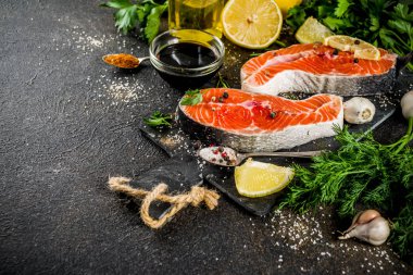 Çiğ Somon Balık biftek ile limon, otlar, zeytin yağı, ızgara, kayrak kesme tahtası, karanlık paslı arka plan kopya alanı için hazır