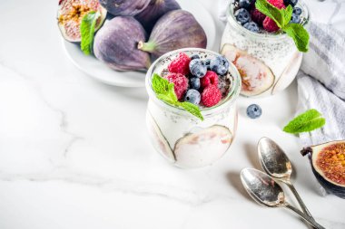 Sağlıklı detoks kahvaltı meze - yoğurt güler yüzlü veya milkshake incir, yaban mersini, ahududu chia tohumu, beyaz mermer zemin, kopya alanı ile
