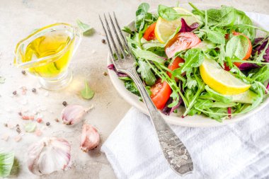 Taze bahar detoks karışımı salata sebze (salatalık, limon, domates, roka ve bebek ıspanak), ışık kayrak, taş veya beton arka plan ile. Üstten görünüm kopya alanı