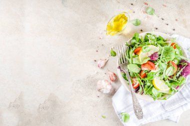 Taze bahar detoks karışımı salata sebze (salatalık, limon, domates, roka ve bebek ıspanak), ışık kayrak, taş veya beton arka plan ile. Üstten görünüm kopya alanı