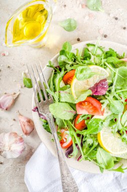 Taze bahar detoks karışımı salata sebze (salatalık, limon, domates, roka ve bebek ıspanak), ışık kayrak, taş veya beton arka plan ile. Üstten görünüm kopya alanı