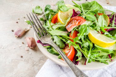 Taze bahar detoks karışımı salata sebze (salatalık, limon, domates, roka ve bebek ıspanak), ışık kayrak, taş veya beton arka plan ile. Üstten görünüm kopya alanı