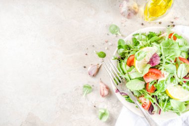 Taze bahar detoks karışımı salata sebze (salatalık, limon, domates, roka ve bebek ıspanak), ışık kayrak, taş veya beton arka plan ile. Üstten görünüm kopya alanı