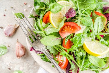 Taze bahar detoks karışımı salata sebze (salatalık, limon, domates, roka ve bebek ıspanak), ışık kayrak, taş veya beton arka plan ile. Üstten görünüm kopya alanı