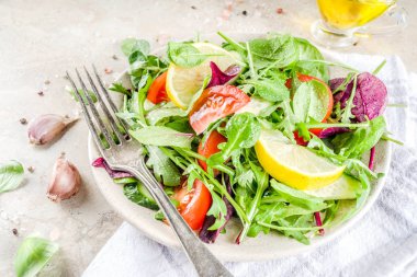 Taze bahar detoks karışımı salata sebze (salatalık, limon, domates, roka ve bebek ıspanak), ışık kayrak, taş veya beton arka plan ile. Üstten görünüm kopya alanı