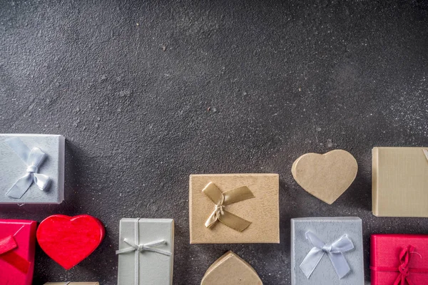 Valentines day gifts boxes background, frame for holiday greeting card background, dark concrete table flat lay, top view, copy space