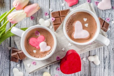Sevgililer günü fikirleri tedavi eder, iki fincan sıcak çikolata ile marshmallow kalpleri ile kırmızı pembe beyaz çikolata parçacıkları, şeker parçacıkları, eski ahşap arka plan fotokopi alanı üst görünümü
