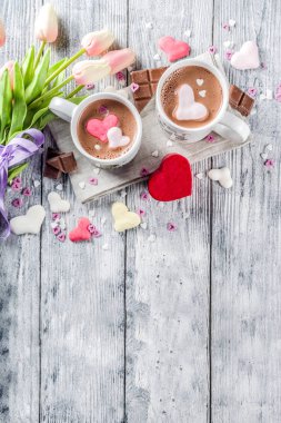 Sevgililer günü fikirleri tedavi eder, iki fincan sıcak çikolata ile marshmallow kalpleri ile kırmızı pembe beyaz çikolata parçacıkları, şeker parçacıkları, eski ahşap arka plan fotokopi alanı üst görünümü