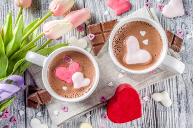 Sevgililer günü fikirleri tedavi eder, iki fincan sıcak çikolata ile marshmallow kalpleri ile kırmızı pembe beyaz çikolata parçacıkları, şeker parçacıkları, eski ahşap arka plan fotokopi alanı üst görünümü