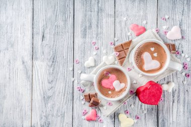 Sevgililer günü fikirleri tedavi eder, iki fincan sıcak çikolata ile marshmallow kalpleri ile kırmızı pembe beyaz çikolata parçacıkları, şeker parçacıkları, eski ahşap arka plan fotokopi alanı üst görünümü