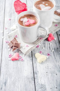 Sevgililer günü fikirleri tedavi eder, iki fincan sıcak çikolata ile marshmallow kalpleri ile kırmızı pembe beyaz çikolata parçacıkları, şeker parçacıkları, eski ahşap arka plan fotokopi alanı üst görünümü