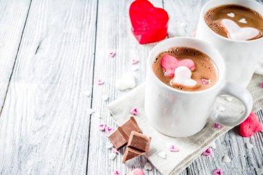 Sevgililer günü fikirleri tedavi eder, iki fincan sıcak çikolata ile marshmallow kalpleri ile kırmızı pembe beyaz çikolata parçacıkları, şeker parçacıkları, eski ahşap arka plan fotokopi alanı üst görünümü
