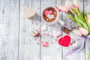 Sevgililer günü fikirleri tedavi eder, iki fincan sıcak çikolata ile marshmallow kalpleri ile kırmızı pembe beyaz çikolata parçacıkları, şeker parçacıkları, eski ahşap arka plan fotokopi alanı üst görünümü