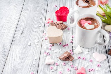 Sevgililer günü fikirleri tedavi eder, iki fincan sıcak çikolata ile marshmallow kalpleri ile kırmızı pembe beyaz çikolata parçacıkları, şeker parçacıkları, eski ahşap arka plan fotokopi alanı üst görünümü