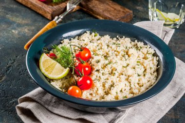 Hafif diyet yiyecekler, kuskus domates, limon ve karanlık kapta taze otlar ile koyu mavi arka plan kopya alanı