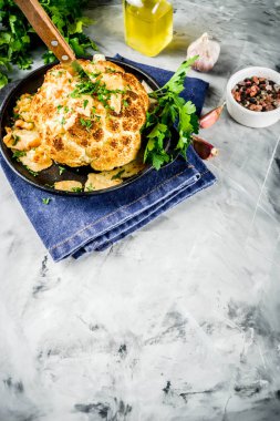 Ev yapımı tüm kavrulmuş karnabahar bir tavada zeytinyağı ve otlar ile. gri taş ya da mermer arka plan kopya alanı